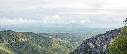 遠くに雲が見える、平野に下りていく丘陵地帯のカラー写真