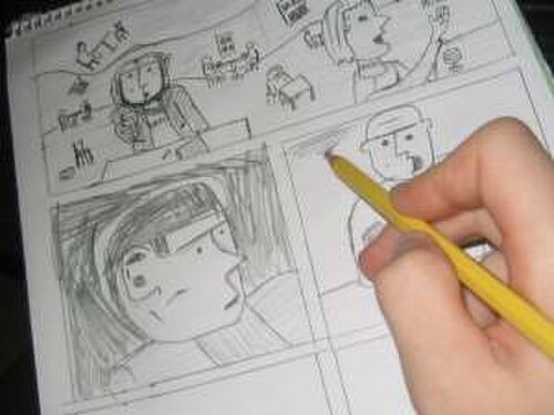 漫画のコマでほぼ埋め尽くされたページに、手が鉛筆で細部を描き込んでいる。