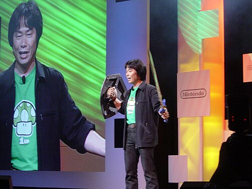 宮本茂氏がリンクの剣と盾のレプリカを持ってステージに立っている