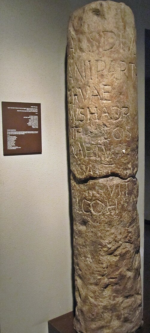 摩耗したラテン語の碑文が刻まれた背の高い石の里程標が、博物館の展示室に直立して展示されている。