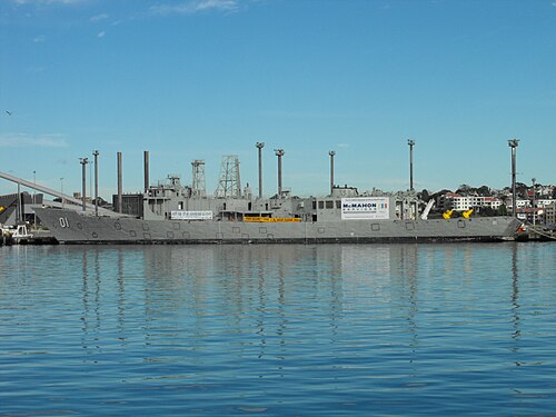 埠頭に係留された小型軍艦。通信マストとレーダーマストは粗雑に小型化され、武器は搭載されておらず、船体には大きな四角い穴がいくつも開けられている。