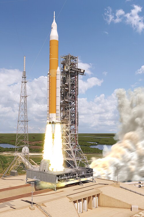 ケネディ宇宙センターの39B発射台から、高い鉄製の支持塔の横にあるオレンジと白の大型ロケットが打ち上げられる。
