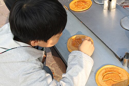 ダルゴナチーズから形を作ろうとしている子供