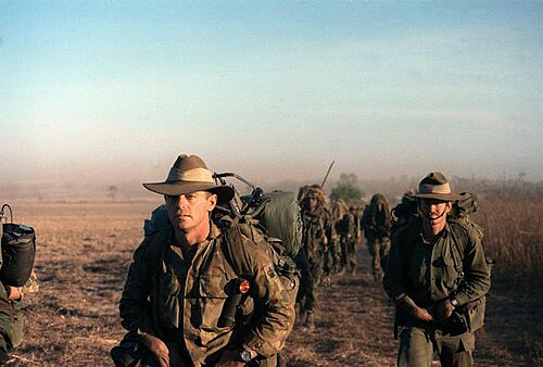 緑の軍服を着た男たちのグループが不毛の地を歩いている。