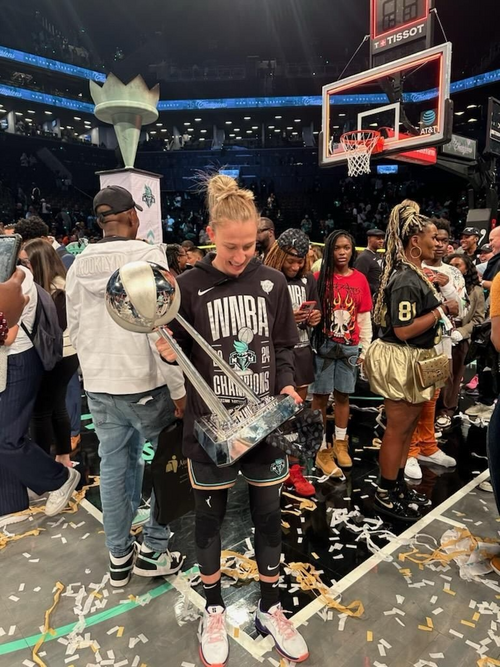 コートニー・ヴァンダースルート選手が、バークレイズ・センターでの勝利後の祝賀会で、ニューヨーク・リバティーズの2024年WNBAチャンピオンシップトロフィーを掲げている。