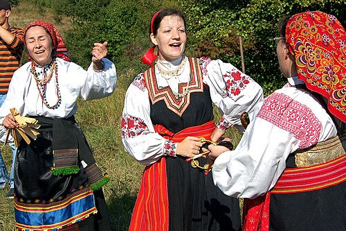 トレシチョーカとスプーン（楽器）を手に持つロシア人女性。右の2人の女性はサラファンを着用しています。