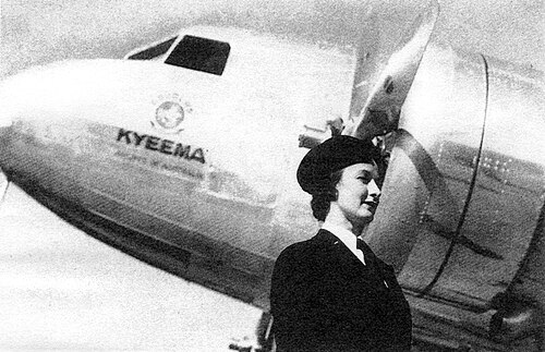 ピストンエンジンの航空機の機首とエンジンの前にある、黒い帽子と制服を着たスチュワーデスの半身肖像画。キエマの名が刻まれている。