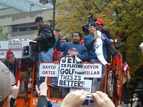 高くなったプラットフォームに集まった男性たち。1 人が「JETER は今日ゴルフをします」と「これはいいことだ!」と書かれた看板を持っています。