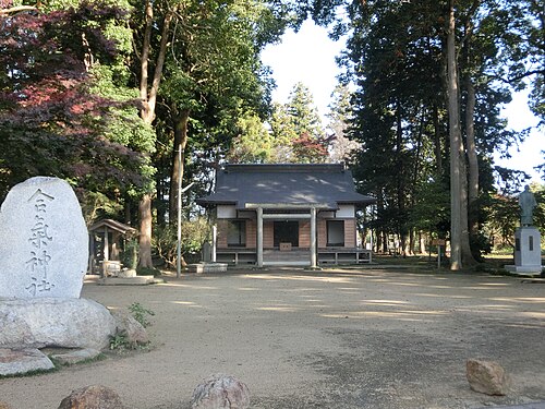 木々に囲まれた小さな神社。手前には石碑が立っている。