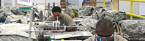 囚人たちがミシンの前に座り、軍服を縫っている