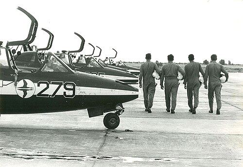 1976年、ハツェリム空軍基地にて、イスラエル空軍曲技飛行チームのパイロット4名とジェット機（二重のガチョウのシンボルを参照）。