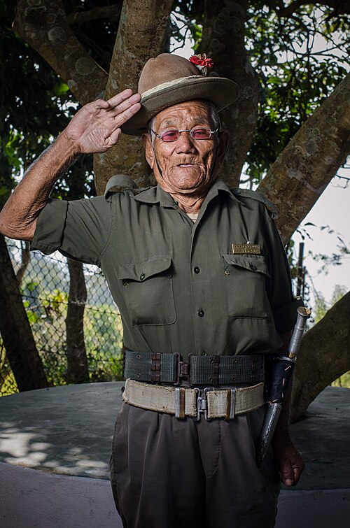 伝統的な制服を着たグルカ兵の退役軍人が直立不動の姿勢で敬礼している。