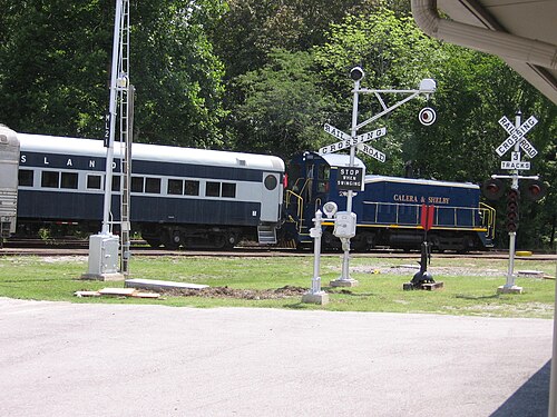 ハート オブ ディキシー鉄道博物館の観光列車が鉄道信号機の表示を過ぎて出発します。