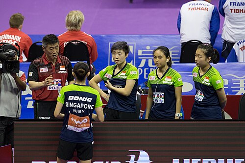 4人の選手がコーチの話を聞いて立っています。