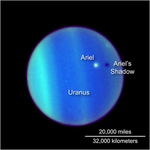 ハッブル望遠鏡を通して見た天王星。その大気は青と緑の帯で表現されている。アリエルは天王星の上に浮かぶ白い点として見え、その下に暗い影を落としている。