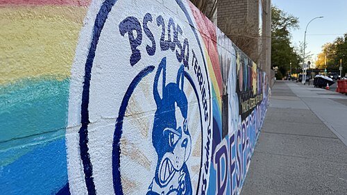 虹色の背景に、中央に犬が描かれた円があり、その周りを「PS 205 Terriers:」という文字が囲んでいるカラフルな壁画。