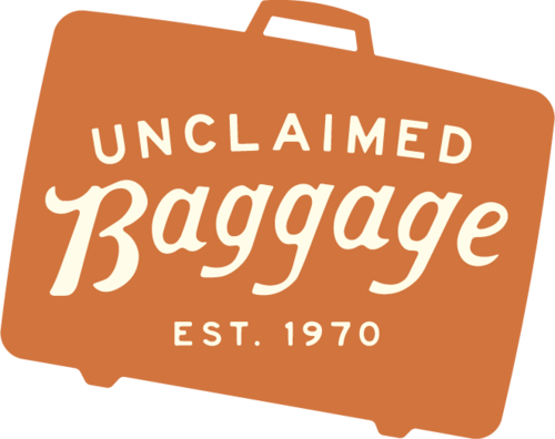 「Unclaimed Baggage, Est. 1970」という文字が書かれたスーツケースのシルエット