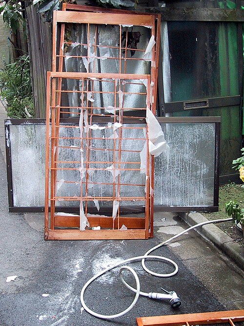 戸口の枠が濡れていて、そこに数枚の紙切れがくっついている。そして、シャワーヘッドが戸口のすぐ外にある。