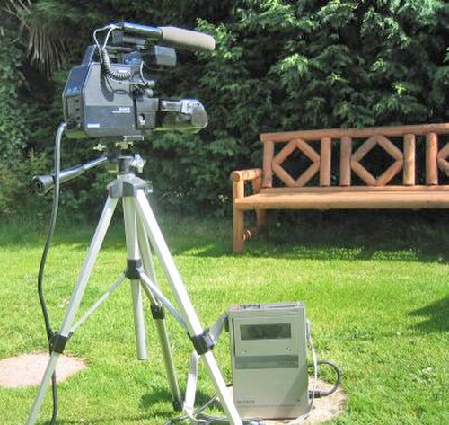 屋外に設置された三脚に取り付けられた大型ビデオカメラ
