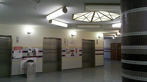 エレベーターホール。室内照明器具のデザインと柱のタイル張りに注目してください。