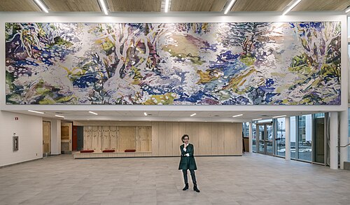スーザン・G・スコットが、新しく設置した壁画「Ruisseau」の前に立っています。