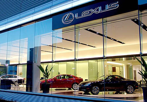 クーペ、セダン 2 台、ガラス窓、そして「Lexus」と書かれた大きな看板を備えた自動車ショールーム。