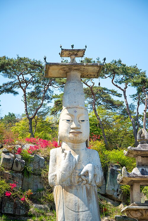 屋外にある、背の高い帽子をかぶった白いアジア人の彫像。