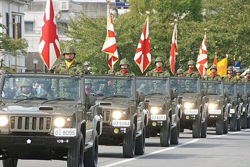 自衛隊旗を掲げた陸上自衛隊車両部隊の行進を観覧