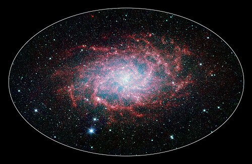 中央には、赤い塵でできた不規則な螺旋状の楕円があり、星々からの青い光の霞がそれを包み込んでいる。周囲の黒い領域には、無数の星が点在している。