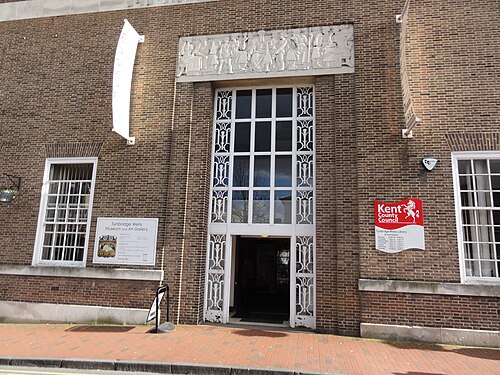 装飾された窓と出入り口上の石のレリーフ彫刻を備えた大きなレンガ造りの建物の入り口