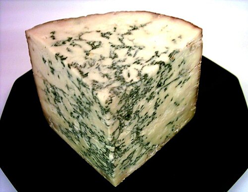 A corner of cheese with greenish streaks through it
