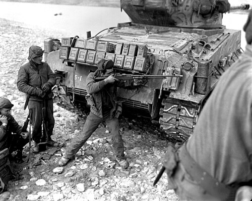 1951年の朝鮮戦争中、M4A3(76)W HVSSシャーマン戦車の後ろからM1918A2ブローニング自動小銃を構える米兵の白黒写真。
