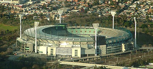 屋外スポーツ スタジアムの航空写真。スタジアムの周囲には 6 つの背の高い懐中電灯が設置されています。スタジアムは住宅、公園、鉄道線路に囲まれています。