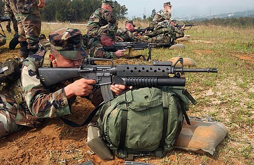 米海兵隊員が、M203 40 mm グレネードランチャーを装備した M16A2 で狙いを定めている。