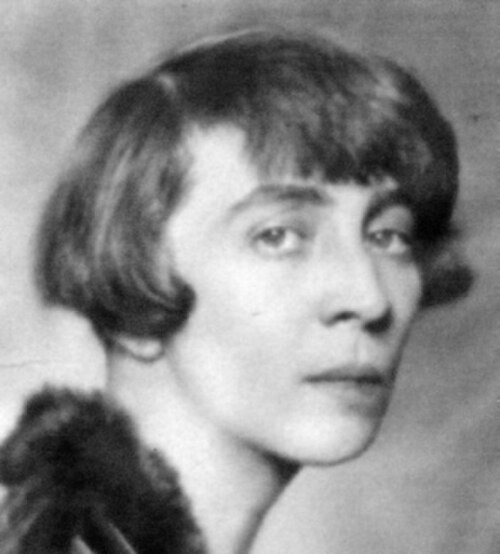 右を向いて横顔で立っている、黒髪をおかっぱ頭にした白人女性。