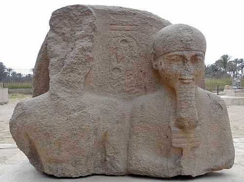 プタハ神を抱くラムセス2世の損傷した像。紀元前1292年～1189年。花崗岩製。メンフィス野外博物館（エジプト）。