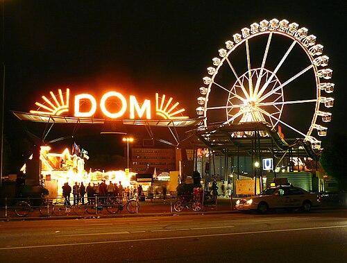 「Dom」という文字が書かれた赤く光る看板と、背景には光る観覧車。