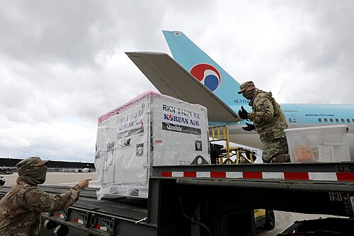 メリーランド州空軍州兵第175航空団の隊員2名が、大韓航空機から新型コロナウイルス検査キットが入った木箱を降ろしている。