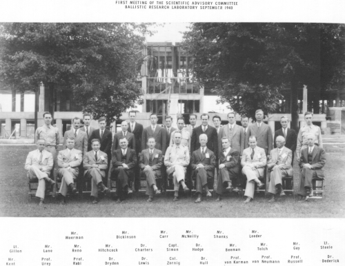 建設中の 328 号館を背景にした科学諮問委員会。後列: モーマン氏、ディキンソン氏、カー氏、マクニーリー氏、シャンクス氏、リーダー氏。中列: ジロン中尉、レーン氏、リノ氏、ヒッチコック氏、チャーターズ博士、サイモン大尉、ホッジ博士、ビーマン氏、トルチ氏、ゲイ氏、スティール中尉。前列: ケント氏、ユーリー教授、ラビ教授、ドライデン博士、ルイス博士、ゾルニグ大佐、ハル博士、フォン カルマン教授、フォン ノイマン教授、ラッセル教授、デデリック博士。
