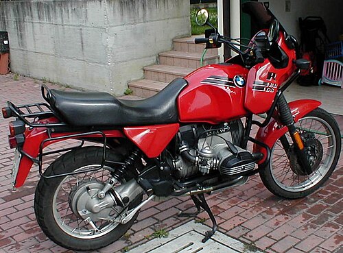 赤い BMW R80GS が階段のある私道に駐車されており、背景にはガレージのドアが開いている。