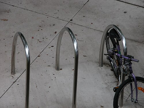 ボルトなしでコンクリートに埋め込まれた 3 つのステンレス製 U リング。右側のリングには自転車がチェーンでつながれています。