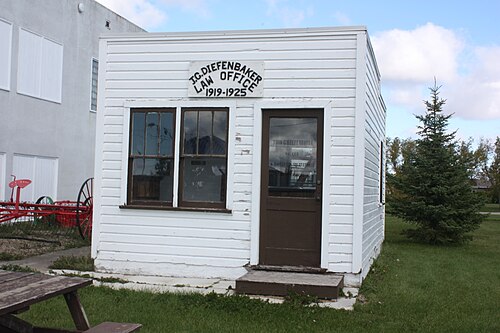 白く塗られた小さな木造の小屋。看板には「JG ディーフェンベーカー法律事務所 1919–1925」とある。