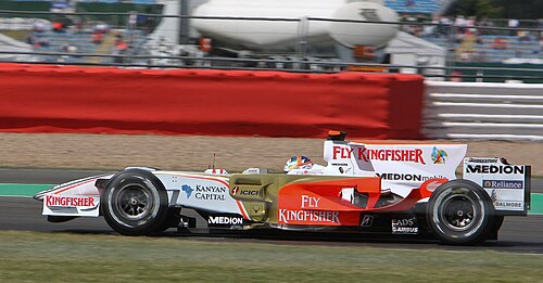 白と金のフォーミュラワンカーがコースを走る