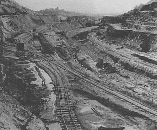 交差する鉄道線路のある丘陵地帯を切り開いて掘削している様子を示す画像。