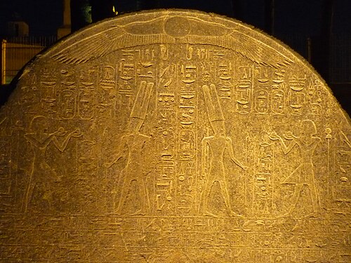 古代エジプトの石碑の上部のルネット。ヒエログリフの縦書きがいっぱいに描かれている。