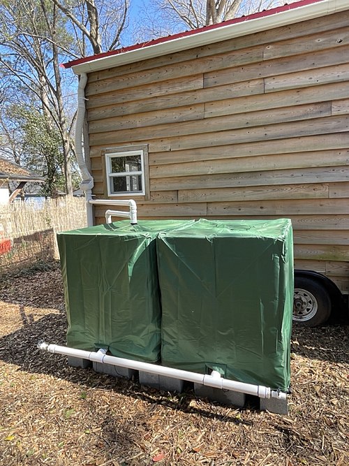 小さな家の屋上から雨水を集め、275 ガロンの IBC トート 2 つに流します。これは、庭や家畜、その他の陸上実験室での使用のために水を貯める手頃な方法です。