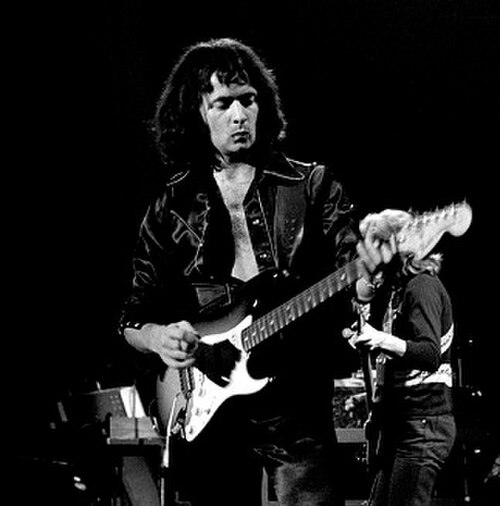 ギタリストのリッチー・ブラックモアがステージ上でフェンダーのエレキギターを演奏している。彼は髪が長い。