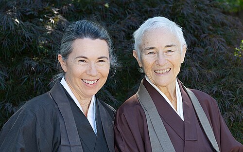 屋外で笑顔を見せる教師のメグ・レヴィさんとジショ・ワーナーさん