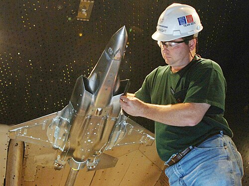 風洞内でジェット戦闘機の金属製スケールモデルを扱うエンジニア