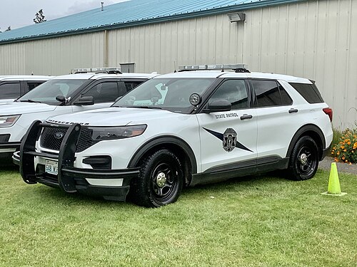 ワシントン州警察のマーキングが施された、白いフォード・エクスプローラータイプのSUV。緊急灯バー、スポットライト、プッシュバーなどの警察用装備が装着されている。